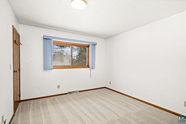 carpeted empty room with visible vents, a textured ceiling, and baseboards