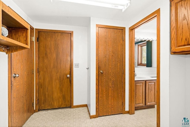 hall featuring light floors and baseboards