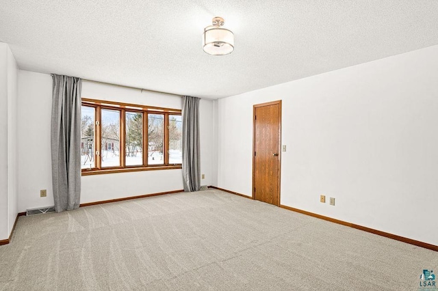 unfurnished room with baseboards, a textured ceiling, visible vents, and light colored carpet