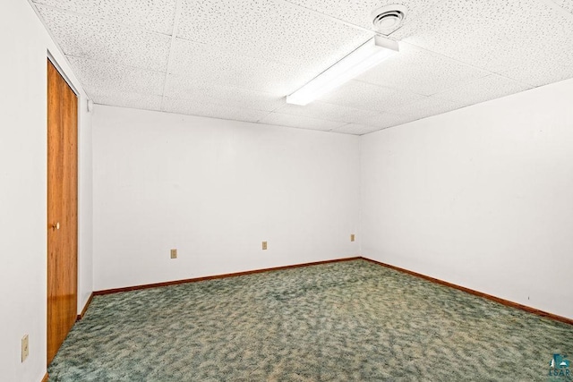 empty room with carpet, a drop ceiling, visible vents, and baseboards