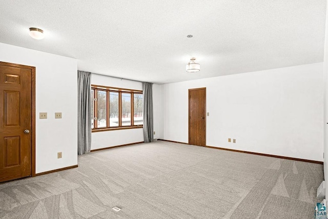 unfurnished room featuring light carpet, baseboards, and a textured ceiling