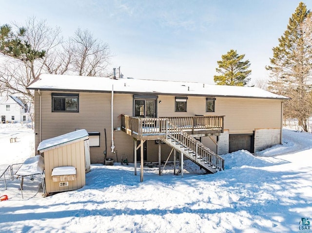 snow covered house with stairway and a wooden deck