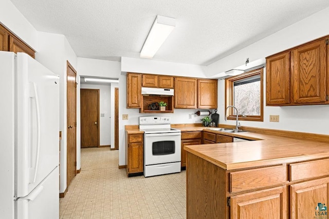 kitchen with under cabinet range hood, a peninsula, white appliances, a sink, and light countertops