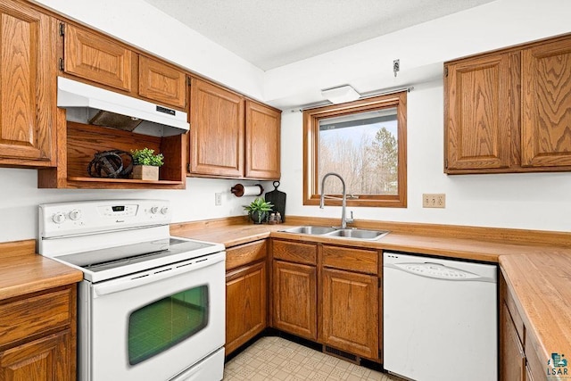 kitchen featuring white appliances, brown cabinetry, light countertops, under cabinet range hood, and a sink