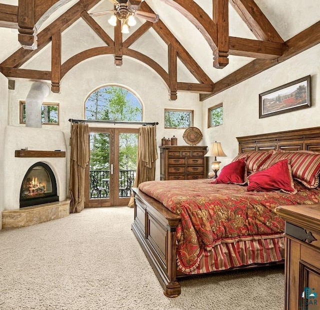 bedroom featuring a warm lit fireplace, carpet, access to outside, high vaulted ceiling, and beam ceiling