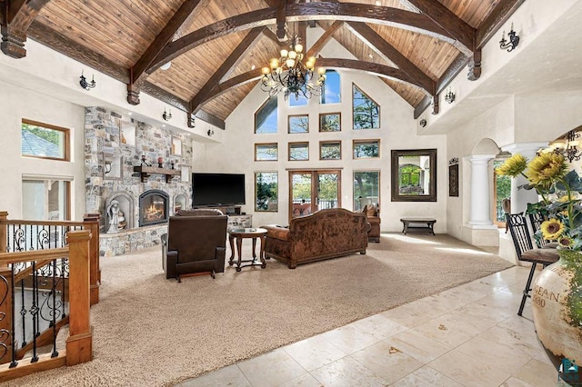 living room featuring a stone fireplace, wood ceiling, ornate columns, beamed ceiling, and an inviting chandelier