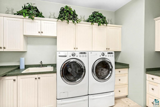 laundry area with cabinet space, separate washer and dryer, and a sink