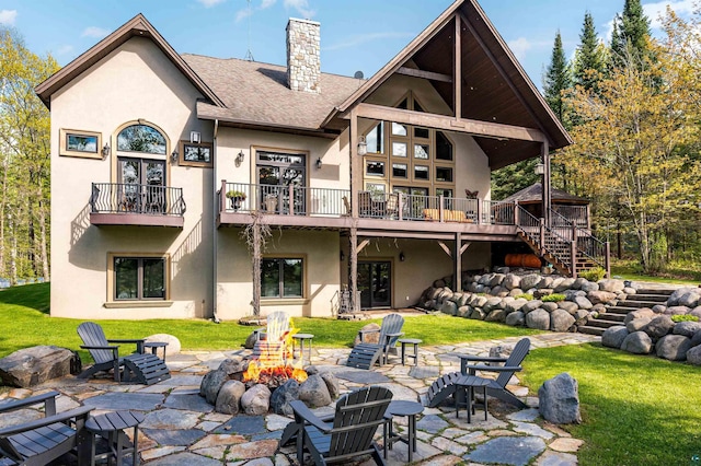 back of property featuring an outdoor fire pit, a chimney, stairway, and stucco siding