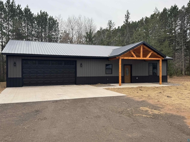 view of front facade featuring a garage, concrete driveway, and metal roof