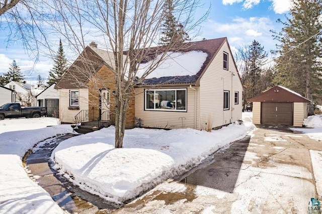 view of front of house featuring a garage, an outbuilding, driveway, and a chimney