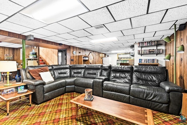 living area featuring stairs, visible vents, and wooden walls