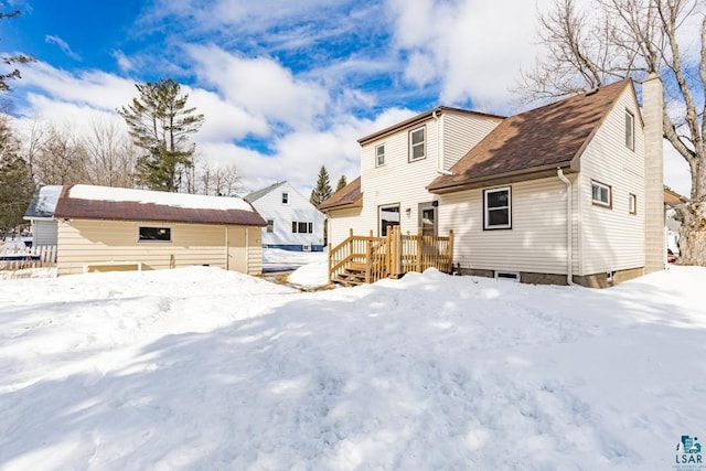 snow covered back of property with a chimney