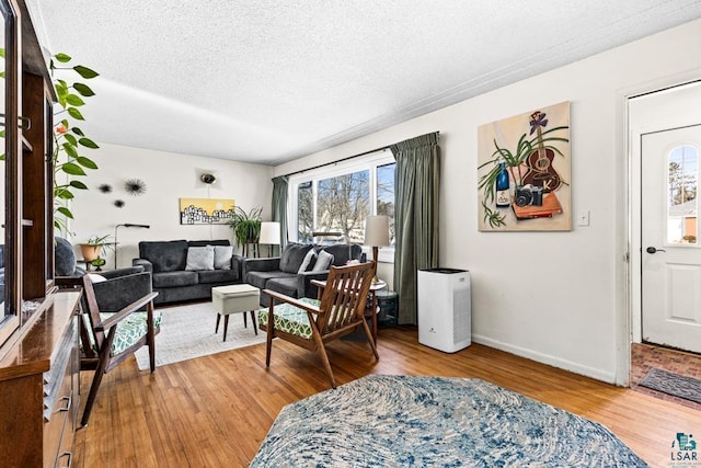 living room featuring a textured ceiling, baseboards, and wood finished floors