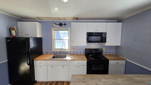 kitchen with black appliances, white cabinetry, wooden counters, and a sink