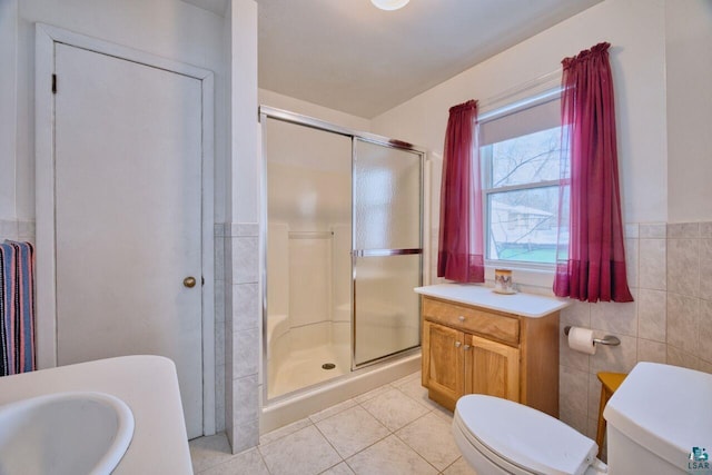 full bathroom with toilet, a stall shower, tile patterned flooring, and tile walls