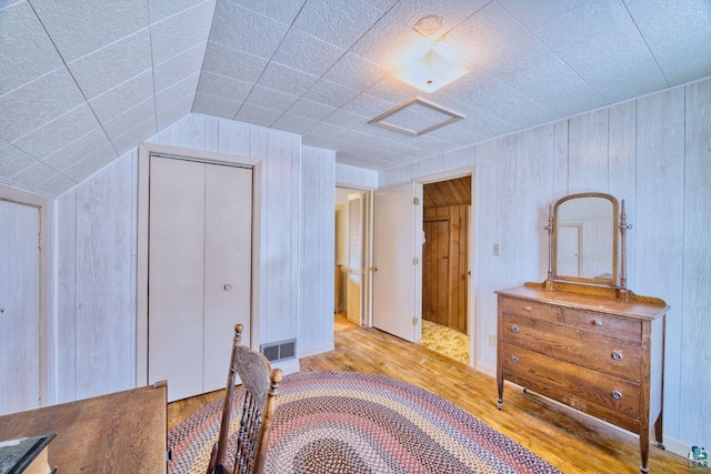 bedroom featuring light wood finished floors, attic access, visible vents, lofted ceiling, and a closet