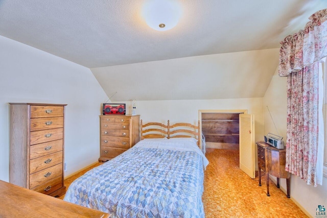 bedroom featuring light carpet, vaulted ceiling, and a textured ceiling