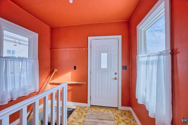 foyer entrance featuring light floors and baseboards