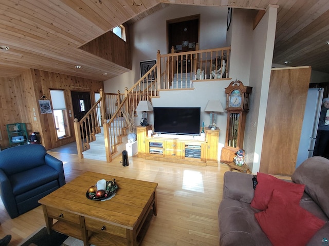 living area featuring light wood-type flooring, a wealth of natural light, wooden ceiling, and stairs