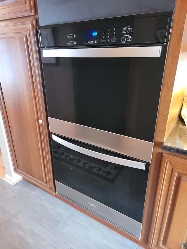 details featuring brown cabinetry, dark stone countertops, and dobule oven black