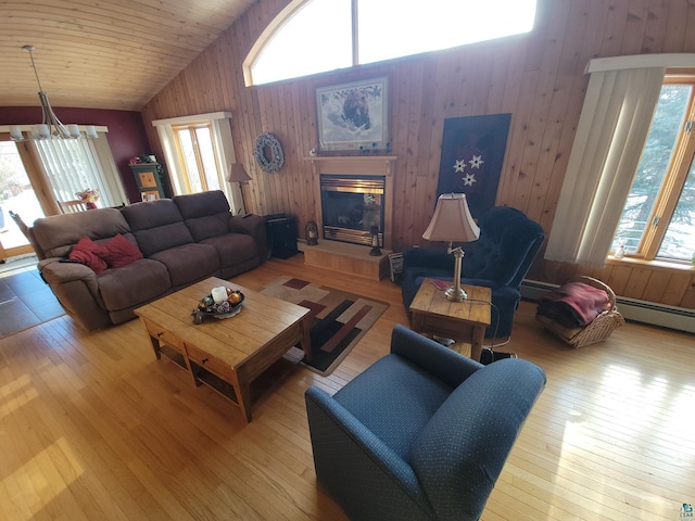 living room with a chandelier, high vaulted ceiling, wooden walls, a fireplace, and wood finished floors