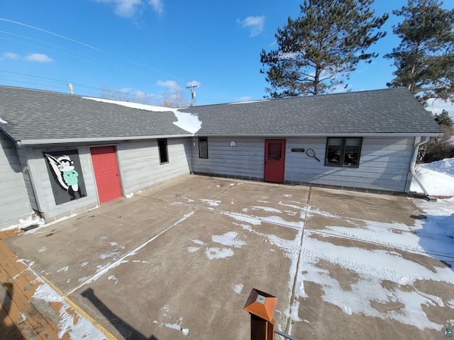 view of front of property featuring a patio area and roof with shingles