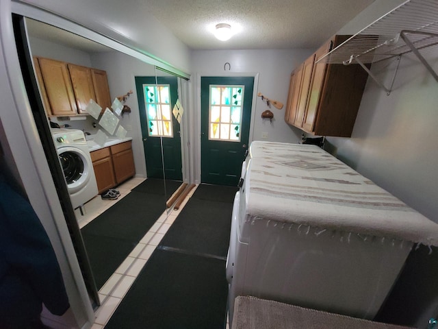 laundry area with cabinet space, washer / clothes dryer, a textured ceiling, and light tile patterned flooring