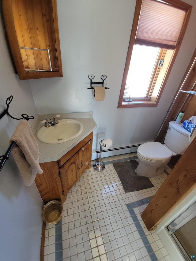 half bathroom with a baseboard heating unit, vanity, toilet, and tile patterned floors