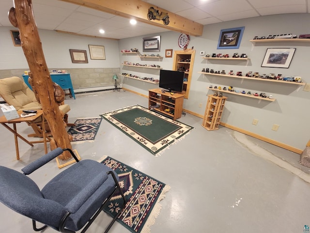 living room featuring finished concrete floors, concrete block wall, a drop ceiling, and baseboards