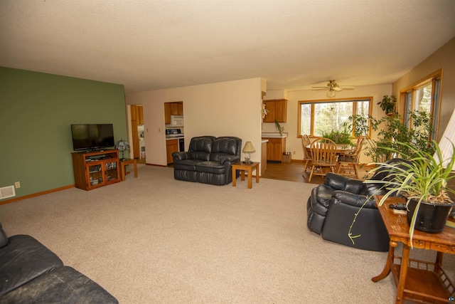 living area with carpet floors, visible vents, a textured ceiling, and baseboards