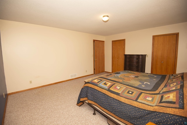 bedroom with multiple closets, carpet, visible vents, and baseboards