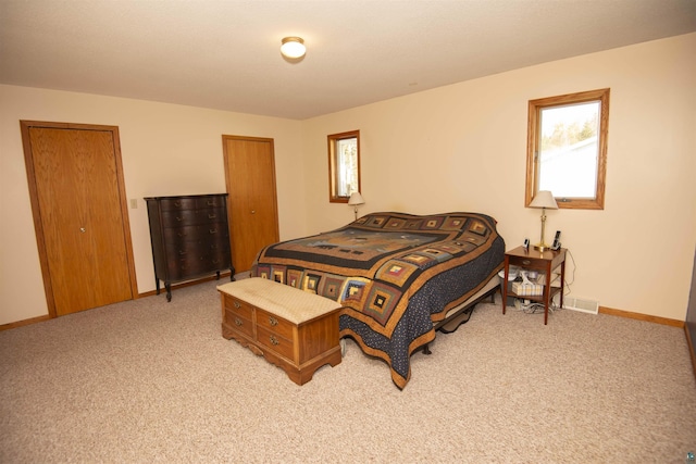 bedroom with light carpet, visible vents, and baseboards