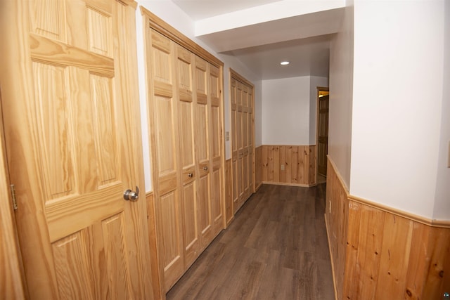 corridor featuring a wainscoted wall, recessed lighting, dark wood finished floors, and wood walls