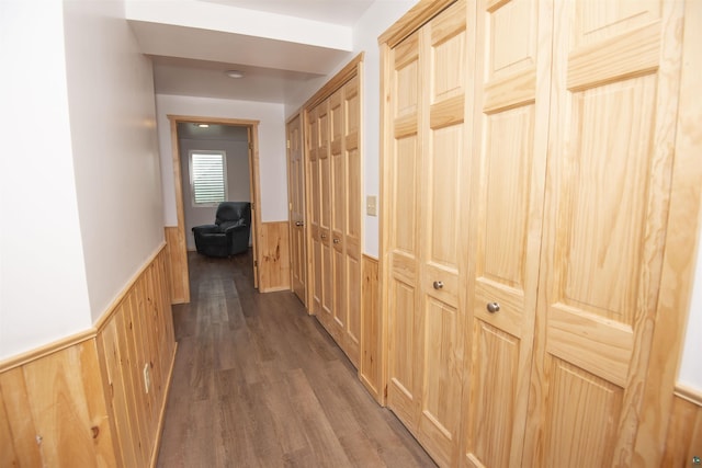 hall featuring wainscoting, wooden walls, and wood finished floors