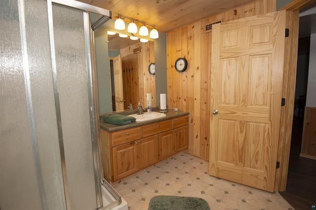 full bath with a stall shower, wooden walls, vanity, and tile patterned floors