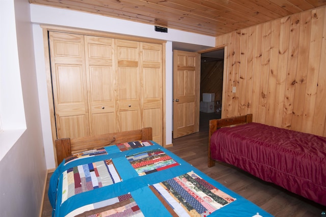 bedroom featuring dark wood-style floors, wood ceiling, a closet, and wooden walls