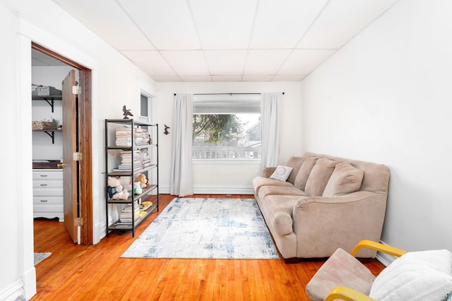 living area with light wood-type flooring and a drop ceiling