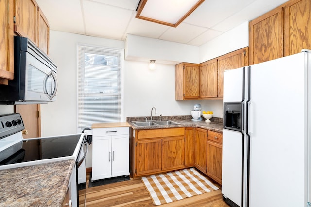 kitchen with electric range oven, dark countertops, stainless steel microwave, white fridge with ice dispenser, and a sink