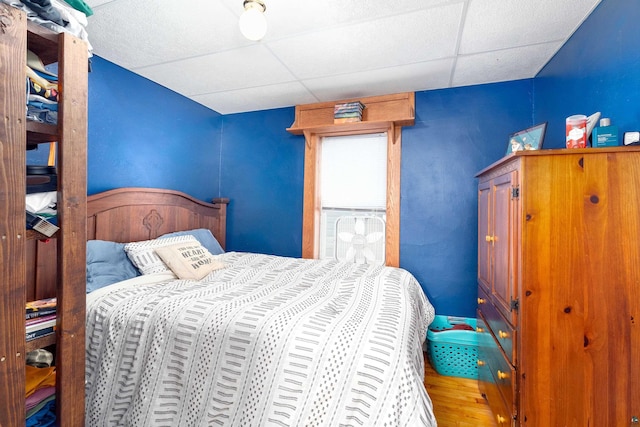 bedroom featuring a drop ceiling and wood finished floors