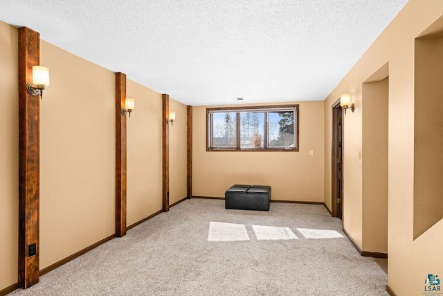 unfurnished room with a textured ceiling, baseboards, and light colored carpet