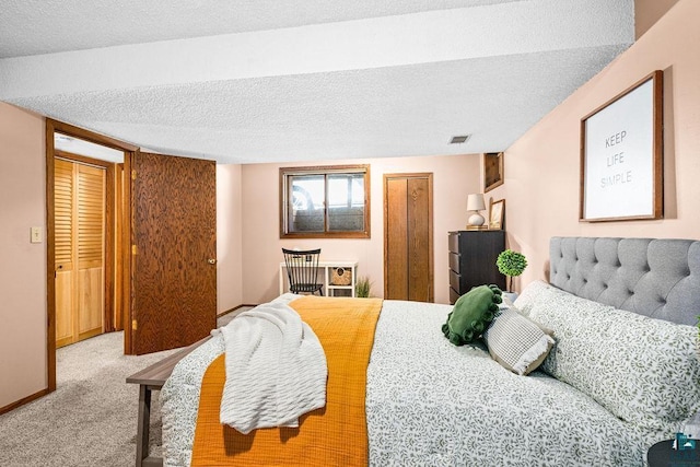 bedroom featuring a textured ceiling, light carpet, visible vents, baseboards, and a closet