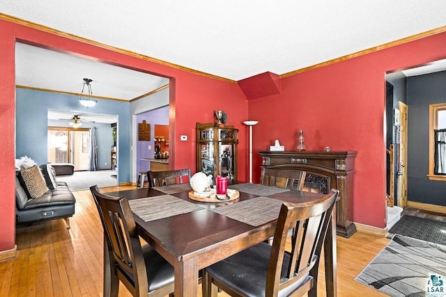 dining area featuring crown molding, baseboards, a ceiling fan, and light wood-style floors