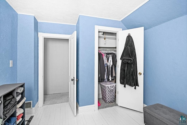 interior space with lofted ceiling, a closet, a textured wall, and wood finished floors