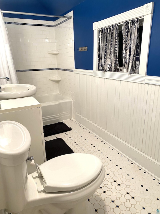 bathroom with shower / bath combination with curtain, a wainscoted wall, vanity, and toilet