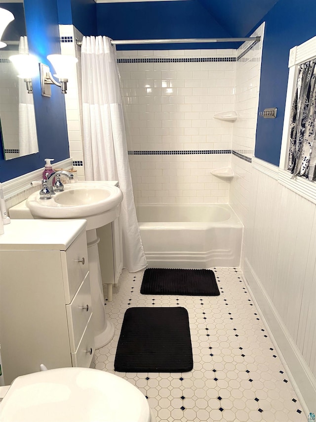 bathroom with shower / bath combo, wainscoting, and vanity