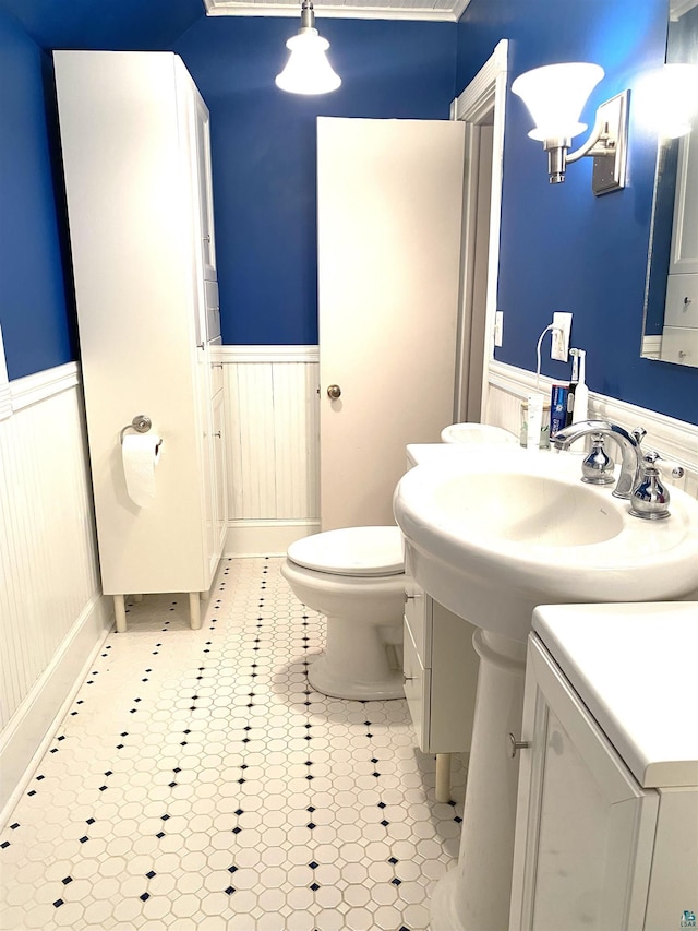 bathroom featuring toilet, a sink, and wainscoting