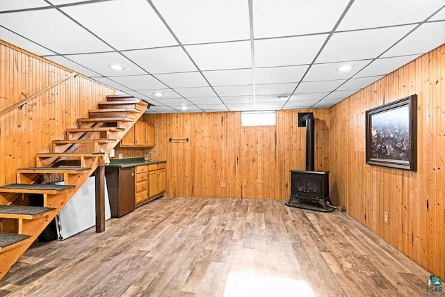 bar with recessed lighting, stairway, light wood-style floors, a wood stove, and wood walls