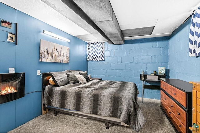 carpeted bedroom with a warm lit fireplace and concrete block wall