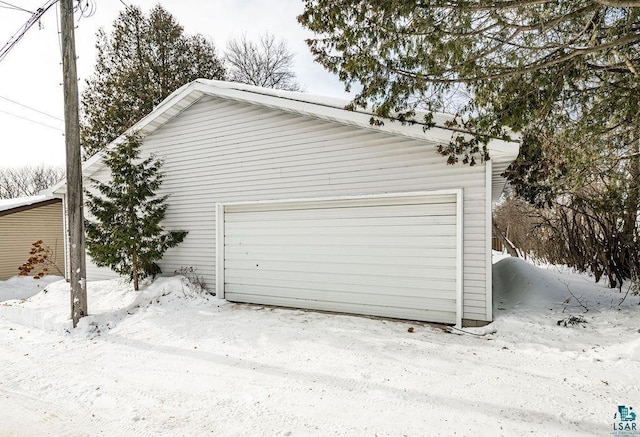 snow covered garage featuring a detached garage