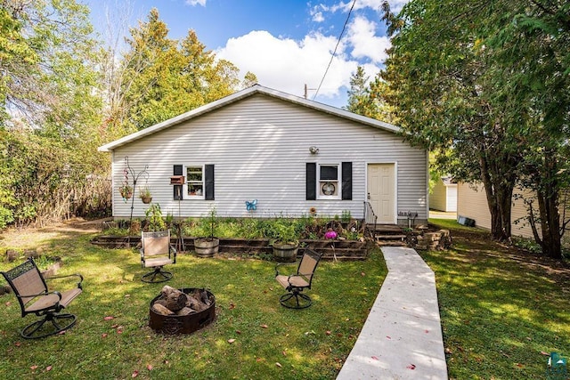 back of property featuring a fire pit and a yard